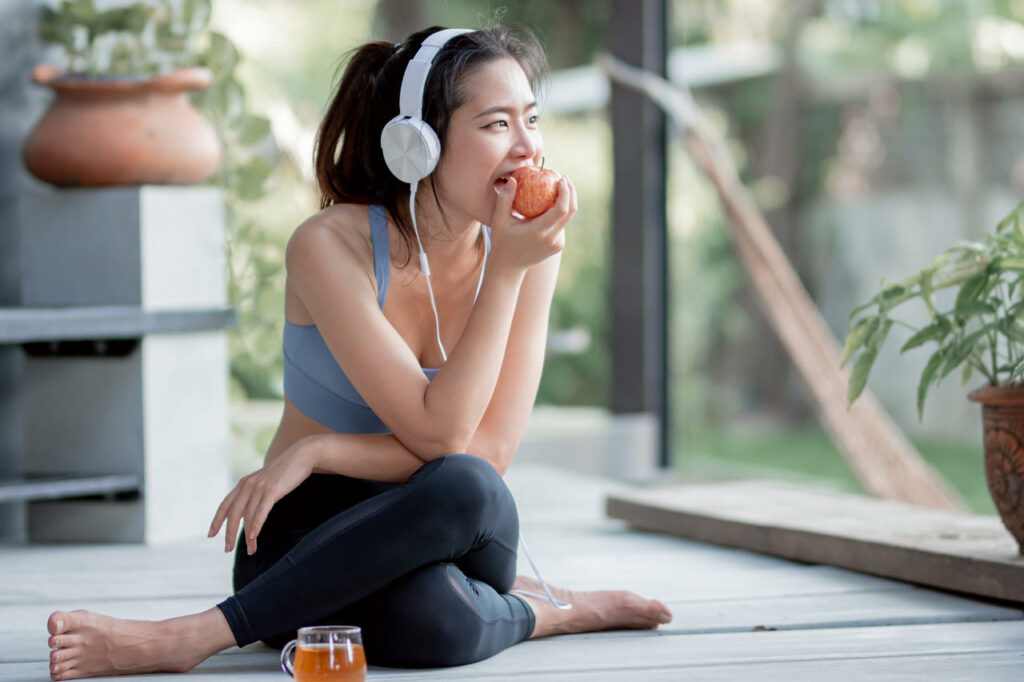 a lady is eating an apple while listening to music after exercising